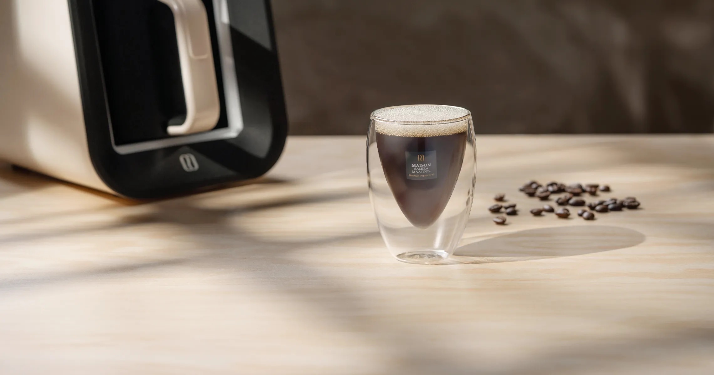 Maison Samira Maatouk coffee with a branded glass cup, coffee machine and roasted beans